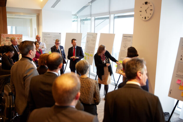 Group of people gathering around a flip-chart looking engaged.