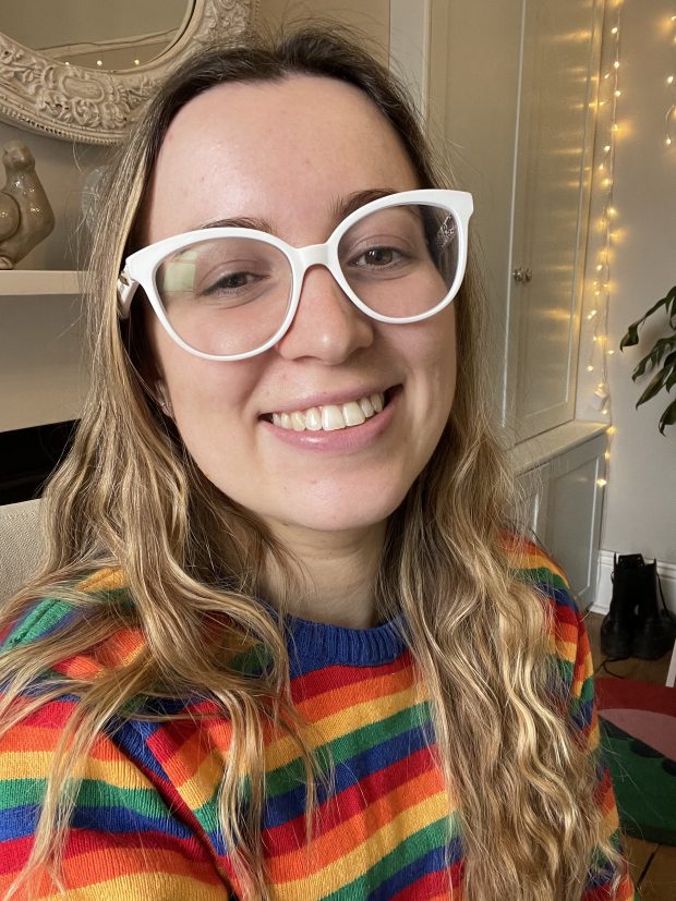 Girl with glasses and wearing a rainbow jumper